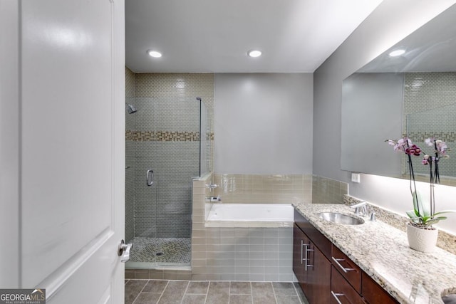 bathroom featuring plus walk in shower, vanity, and tile patterned flooring