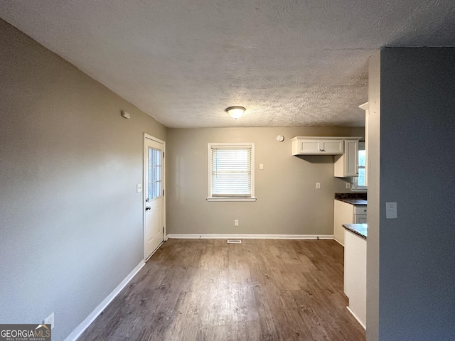 unfurnished dining area featuring a textured ceiling and dark wood-type flooring