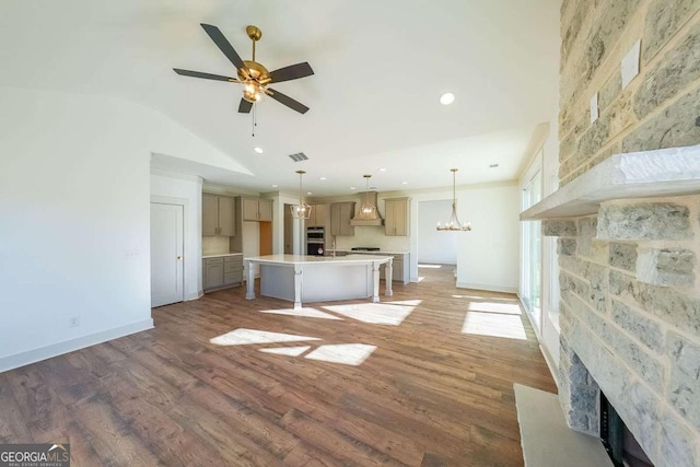 unfurnished living room with ceiling fan with notable chandelier, hardwood / wood-style flooring, and lofted ceiling