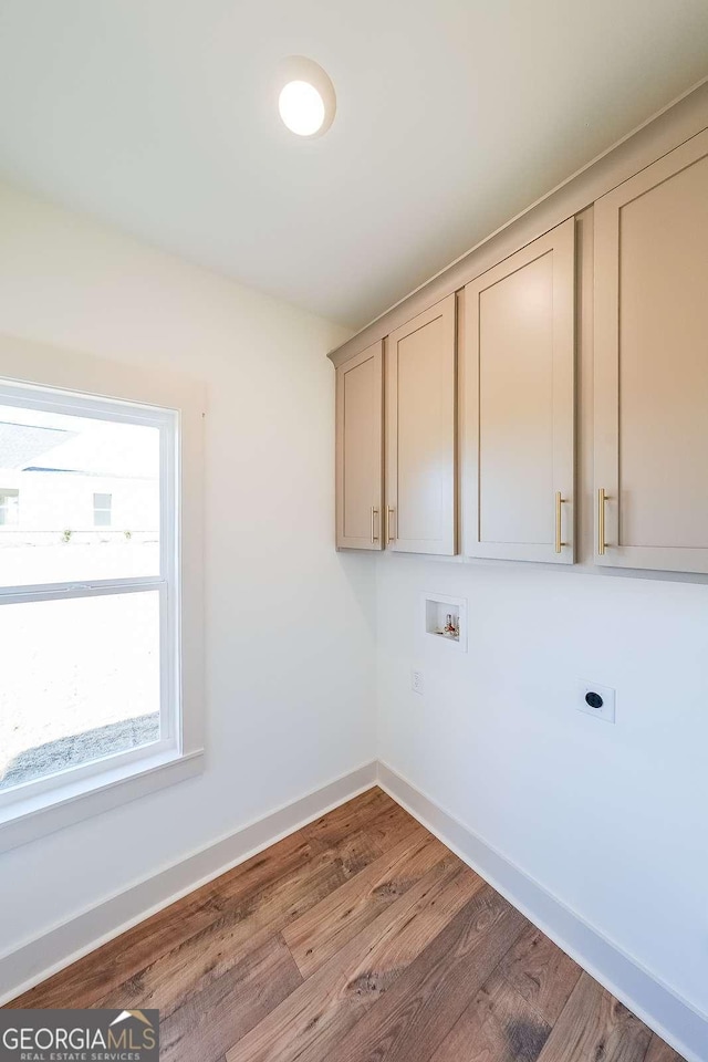 washroom featuring hookup for a washing machine, wood-type flooring, cabinets, and hookup for an electric dryer