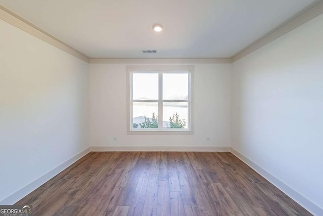 empty room featuring dark hardwood / wood-style floors and crown molding