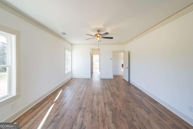 empty room featuring wood-type flooring, crown molding, and a wealth of natural light