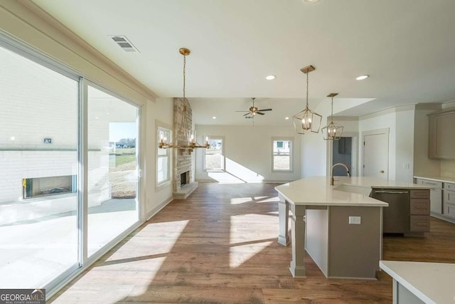 kitchen featuring a fireplace, dishwasher, plenty of natural light, and a kitchen island with sink