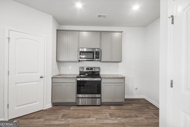 kitchen featuring gray cabinetry, light stone countertops, dark hardwood / wood-style flooring, and stainless steel appliances