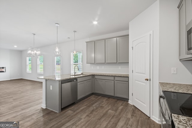 kitchen featuring kitchen peninsula, light stone counters, sink, dishwasher, and hanging light fixtures