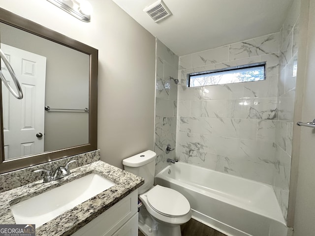 full bathroom featuring vanity, tiled shower / bath combo, and toilet