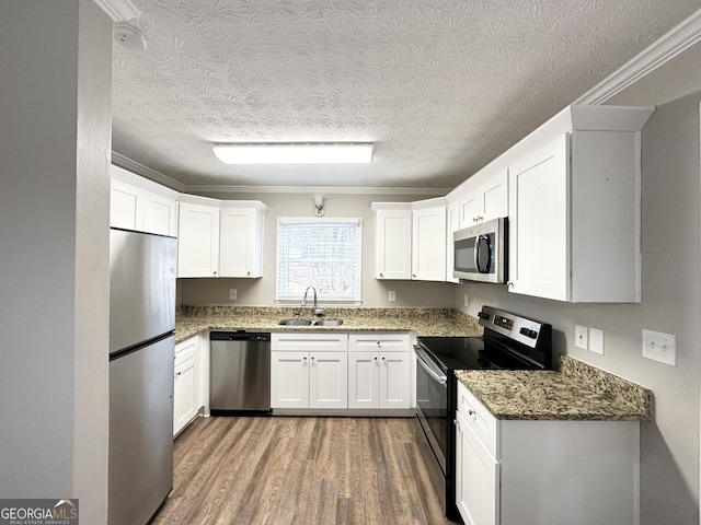 kitchen with white cabinets, appliances with stainless steel finishes, ornamental molding, and sink