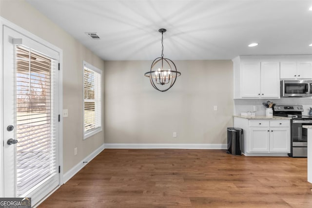 kitchen with white cabinetry, hanging light fixtures, an inviting chandelier, wood-type flooring, and appliances with stainless steel finishes