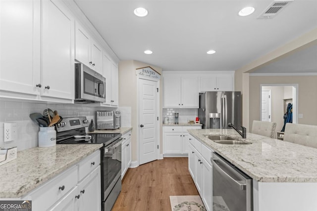 kitchen with decorative backsplash, appliances with stainless steel finishes, crown molding, sink, and white cabinets