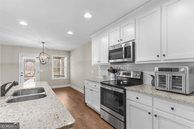 kitchen featuring white cabinets, appliances with stainless steel finishes, a chandelier, and sink