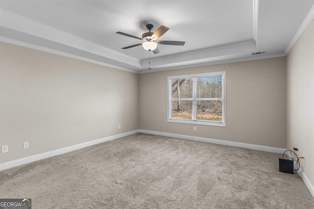 carpeted empty room with a tray ceiling, ceiling fan, and ornamental molding