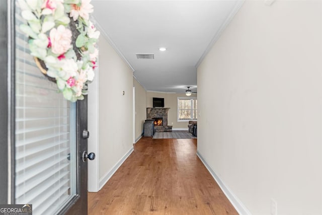 corridor with light hardwood / wood-style flooring and ornamental molding