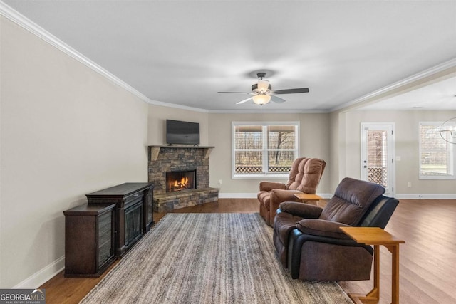 living room featuring hardwood / wood-style flooring, ceiling fan with notable chandelier, crown molding, and a fireplace