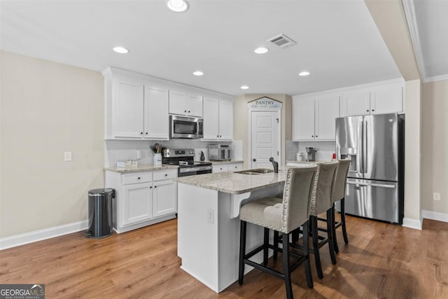 kitchen with white cabinets, stainless steel appliances, and a kitchen island with sink