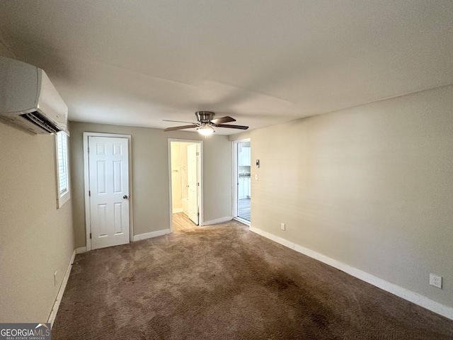 unfurnished bedroom with an AC wall unit, ensuite bath, ceiling fan, and carpet flooring