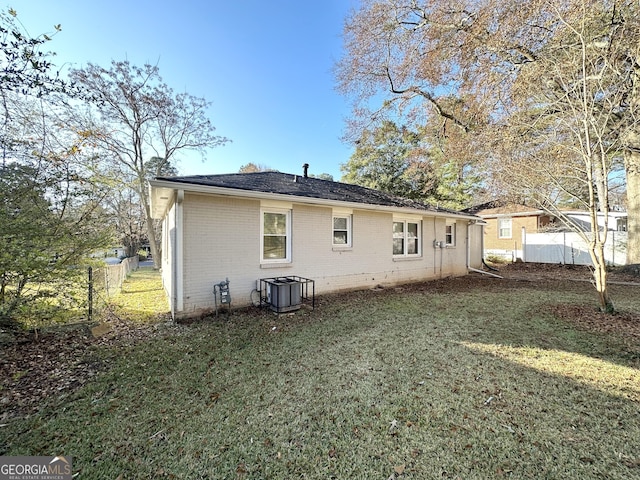 rear view of house with a lawn and central air condition unit