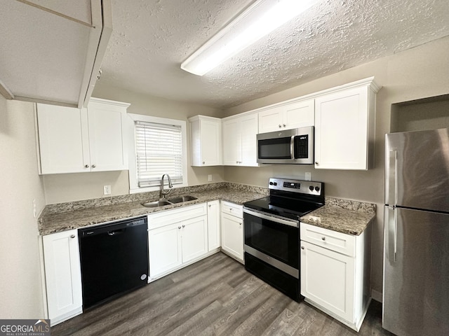 kitchen with white cabinets, dark stone countertops, sink, and stainless steel appliances