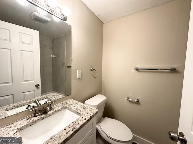 bathroom with a tile shower, vanity, and toilet