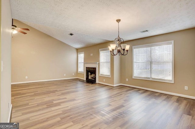 unfurnished living room featuring hardwood / wood-style floors, a textured ceiling, a high end fireplace, and vaulted ceiling