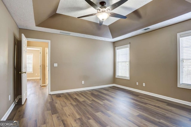 empty room featuring ceiling fan, a raised ceiling, and a textured ceiling