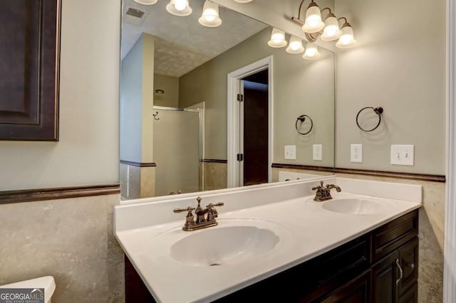 bathroom with a textured ceiling, vanity, and walk in shower