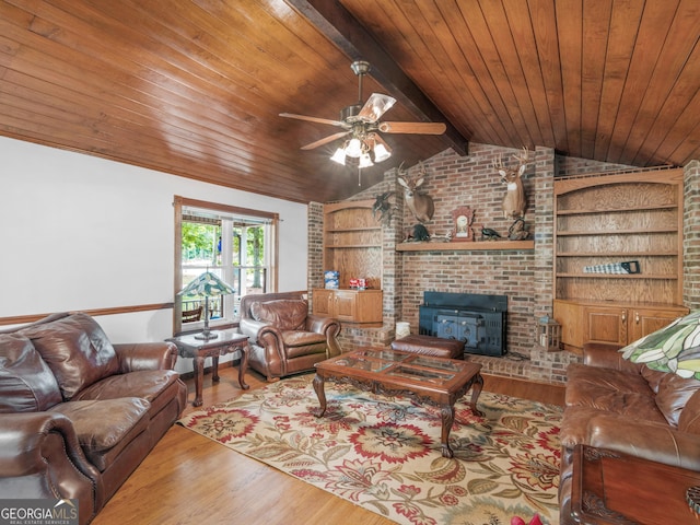 living room with built in shelves, light hardwood / wood-style floors, a wood stove, and wood ceiling