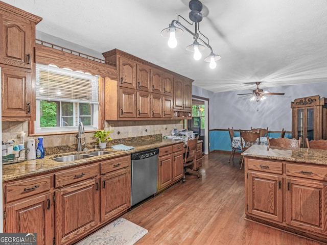 kitchen featuring light wood-type flooring, stainless steel dishwasher, a wealth of natural light, sink, and hanging light fixtures