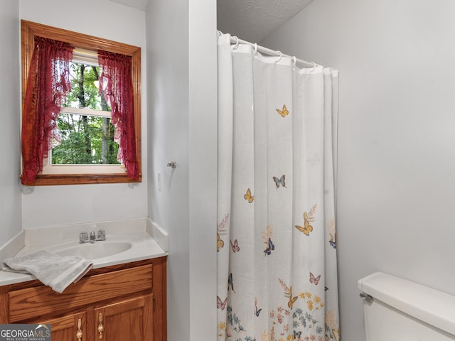 bathroom featuring curtained shower, vanity, a textured ceiling, and toilet