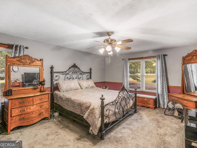 carpeted bedroom with ceiling fan and a textured ceiling