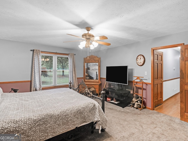 carpeted bedroom featuring ceiling fan and a textured ceiling