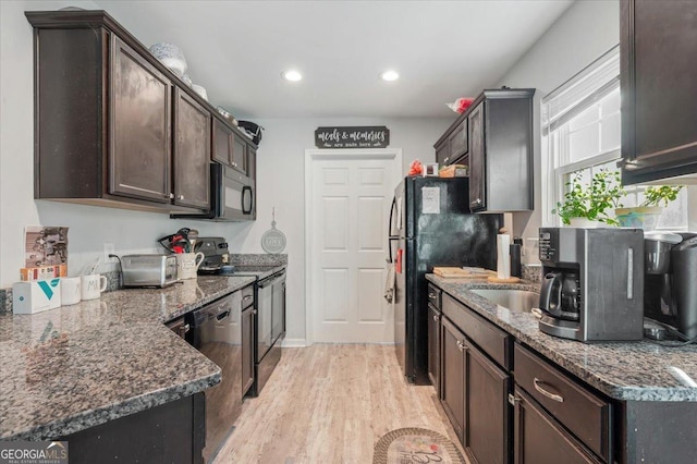 kitchen with dark brown cabinetry, light hardwood / wood-style floors, and black appliances