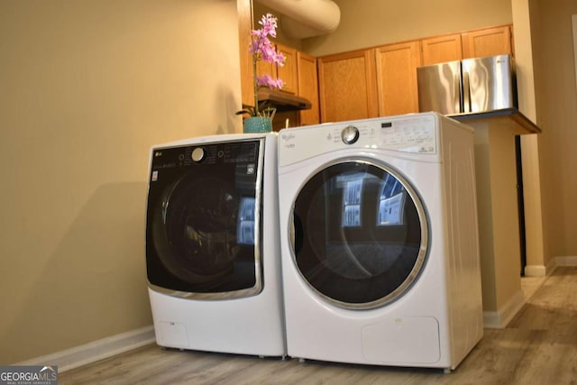 clothes washing area with washer and dryer and light hardwood / wood-style floors