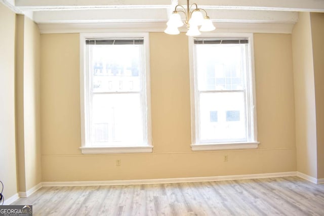 unfurnished room with light hardwood / wood-style floors, a healthy amount of sunlight, and an inviting chandelier