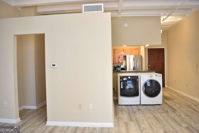 washroom featuring washer and dryer, a high ceiling, and light wood-type flooring