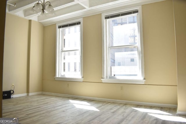 unfurnished room featuring a wealth of natural light, light hardwood / wood-style flooring, and a notable chandelier