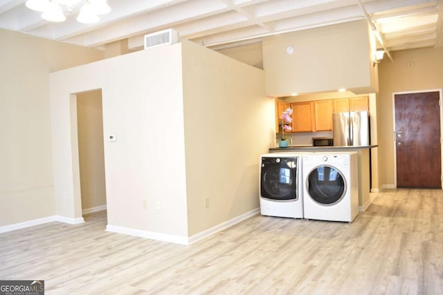 laundry area featuring washer and clothes dryer, light hardwood / wood-style floors, and cabinets