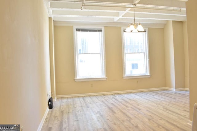 spare room featuring light wood-type flooring and an inviting chandelier