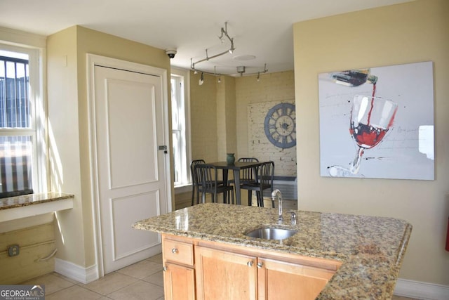 kitchen featuring sink, rail lighting, light brown cabinets, light stone counters, and light tile patterned flooring