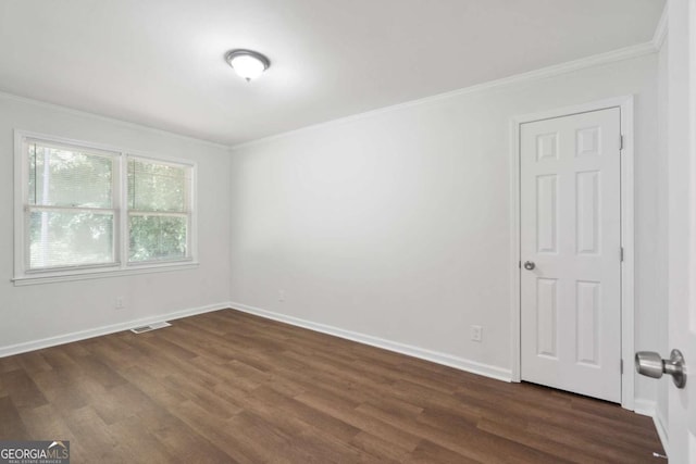 spare room featuring dark hardwood / wood-style flooring and crown molding