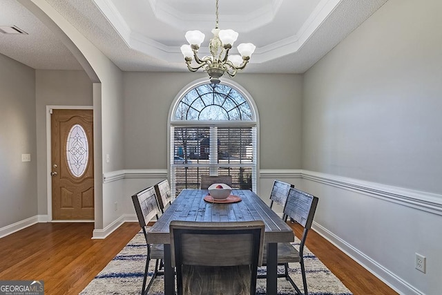 dining area featuring a tray ceiling, an inviting chandelier, and dark hardwood / wood-style floors