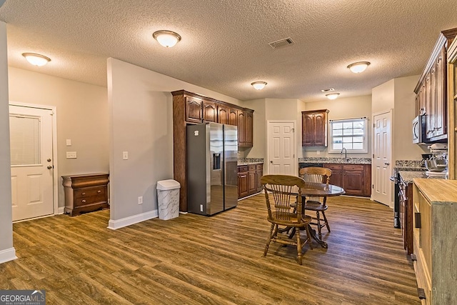 kitchen featuring dark wood-type flooring, sink, a textured ceiling, dark brown cabinets, and stainless steel appliances