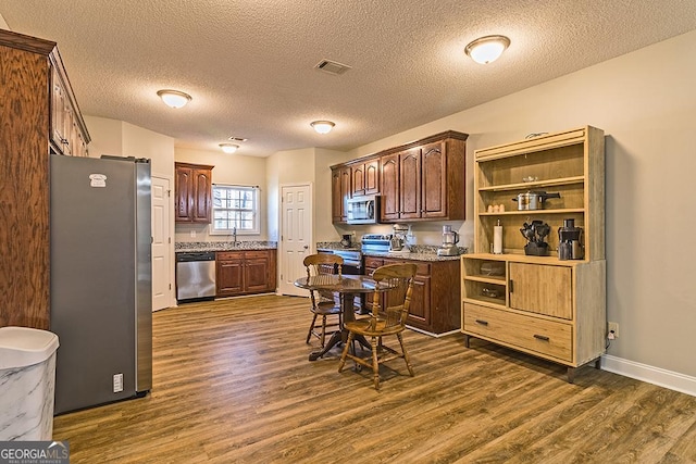 kitchen with dark hardwood / wood-style floors, a textured ceiling, and appliances with stainless steel finishes