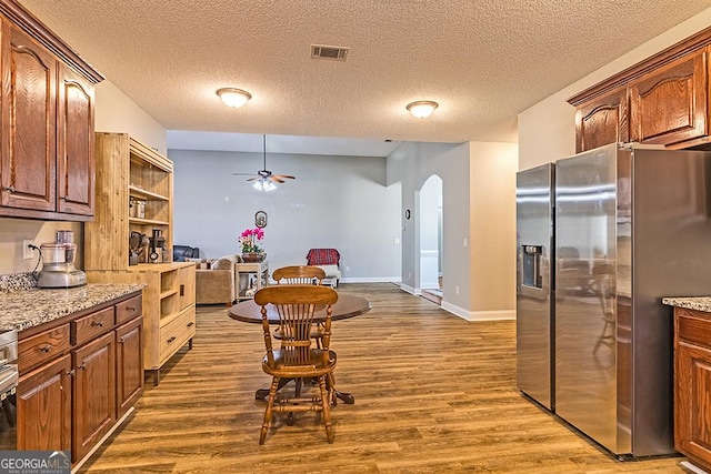 kitchen with light stone countertops, stainless steel refrigerator with ice dispenser, dark hardwood / wood-style flooring, and a textured ceiling