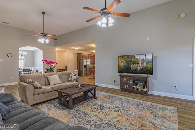 living room featuring hardwood / wood-style floors, high vaulted ceiling, and ceiling fan with notable chandelier