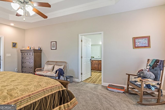 bedroom featuring a tray ceiling, ensuite bath, ceiling fan, and light colored carpet