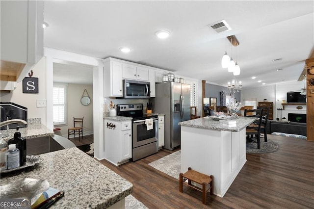 kitchen with light stone counters, white cabinets, pendant lighting, and appliances with stainless steel finishes