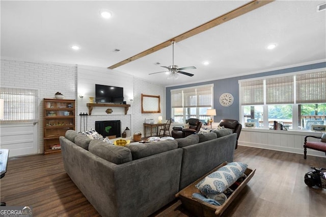 living room with a healthy amount of sunlight, dark wood-type flooring, brick wall, and a brick fireplace