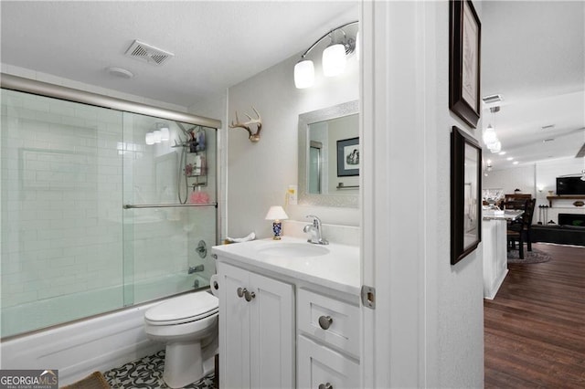 full bathroom featuring vanity, hardwood / wood-style flooring, toilet, and enclosed tub / shower combo