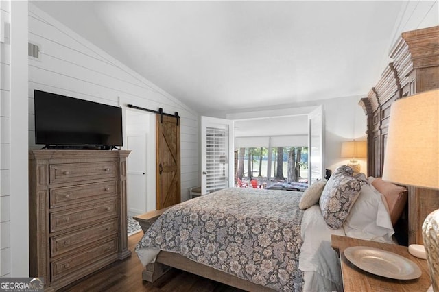 bedroom featuring a barn door, dark hardwood / wood-style floors, lofted ceiling, and access to exterior