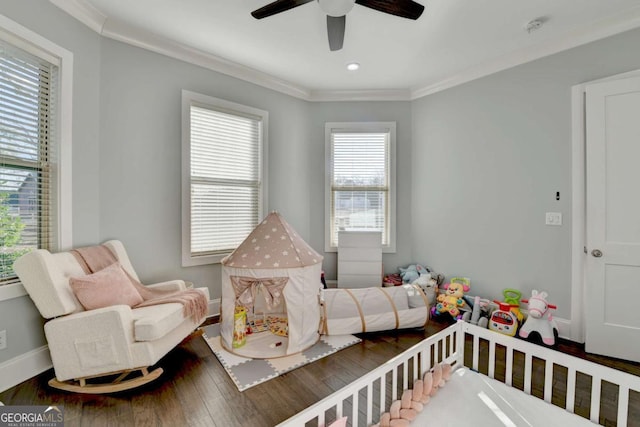 bedroom featuring hardwood / wood-style flooring, ceiling fan, crown molding, and a nursery area